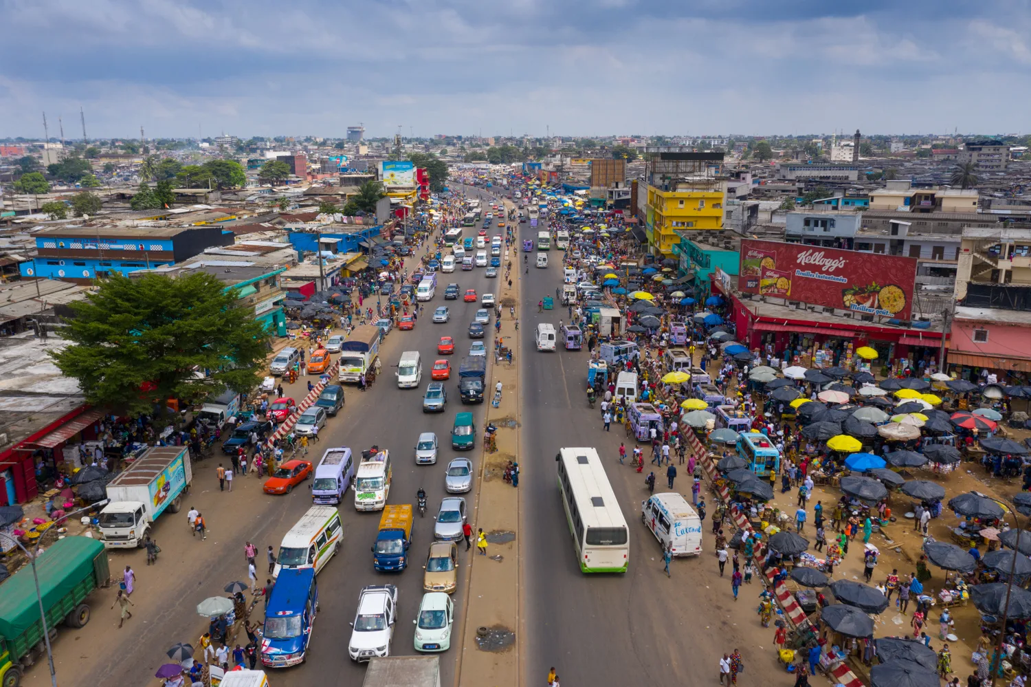 Africa photo — Image aérienne montrant une large avenue très fréquentée avec des marchés de part et d'autre, des étals ombragés par des parasols color