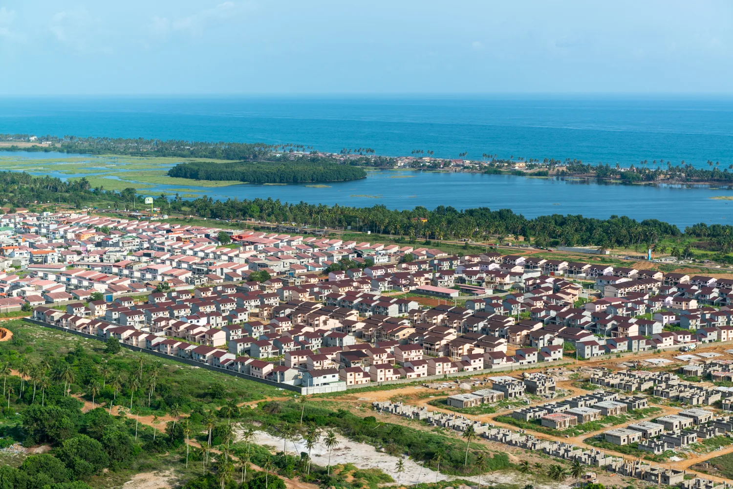 Africa photo — Vue aérienne d’un quartier résidentiel composé de maisons individuelles aux toits rouges et blancs, entouré de végétation tropicale, av