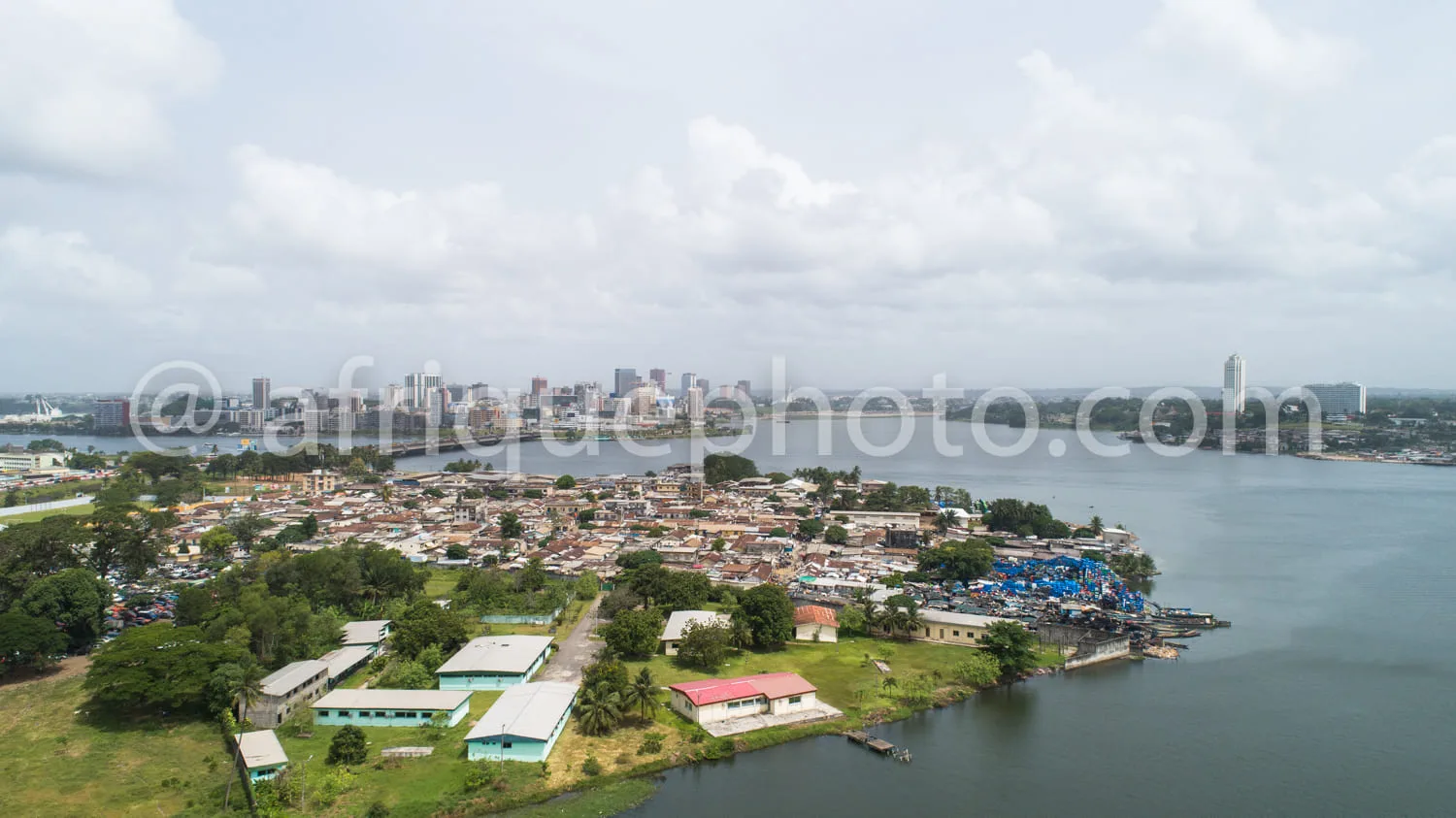 Africa photo — Image aérienne montrant une ville côtière avec un port en bas à droite, des habitations précaires en premier plan, des bâtiments admini