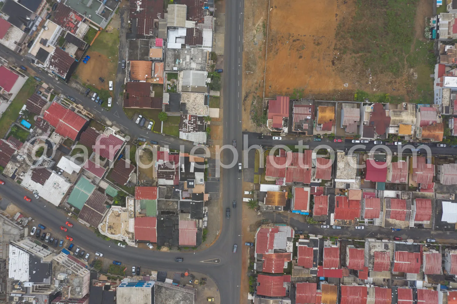 Africa photo — Image prise depuis les airs montrant un quartier résidentiel avec des maisons aux toits rouges et des murs de différentes couleurs. Une