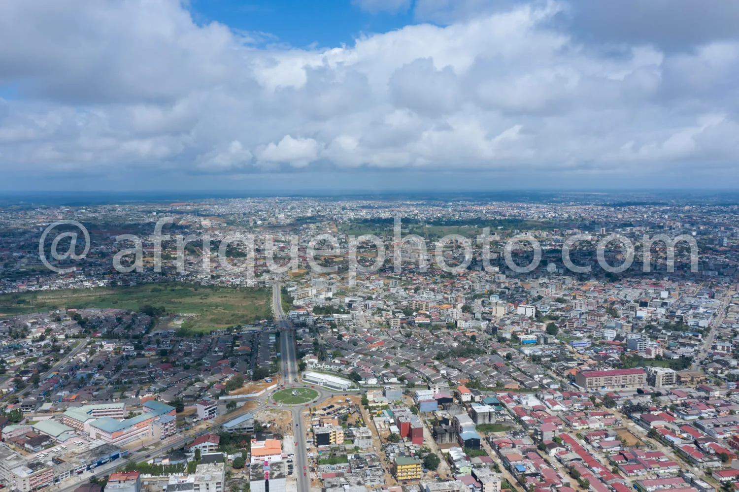 Africa photo — Image montrant une ville étendue avec des maisons serrées, des routes principales et un grand espace vert central, sous un ciel partiel