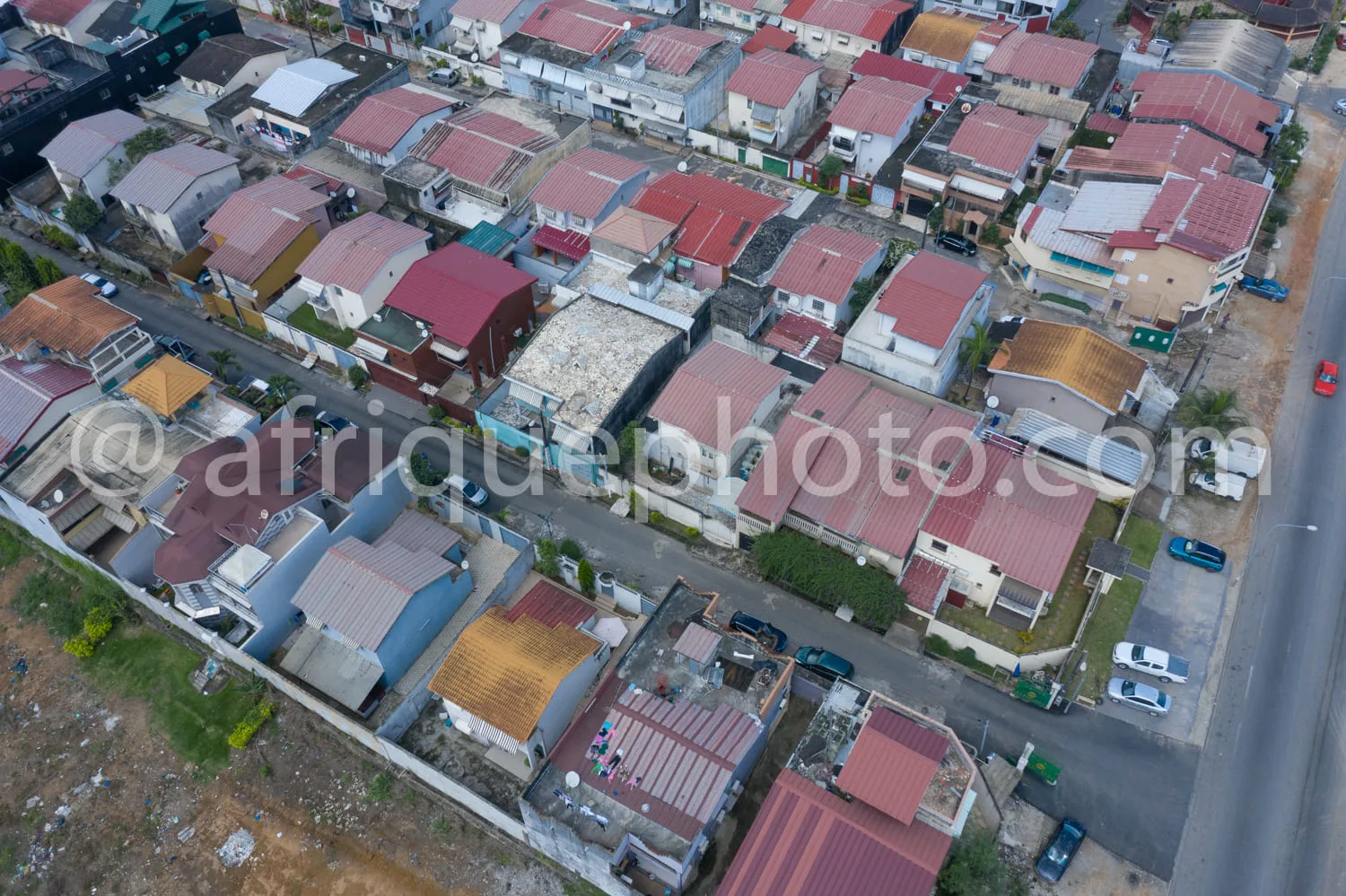 Africa photo — Vue aérienne d’un quartier résidentiel composé de maisons individuelles aux toits colorés, principalement rouges et blancs, organisées