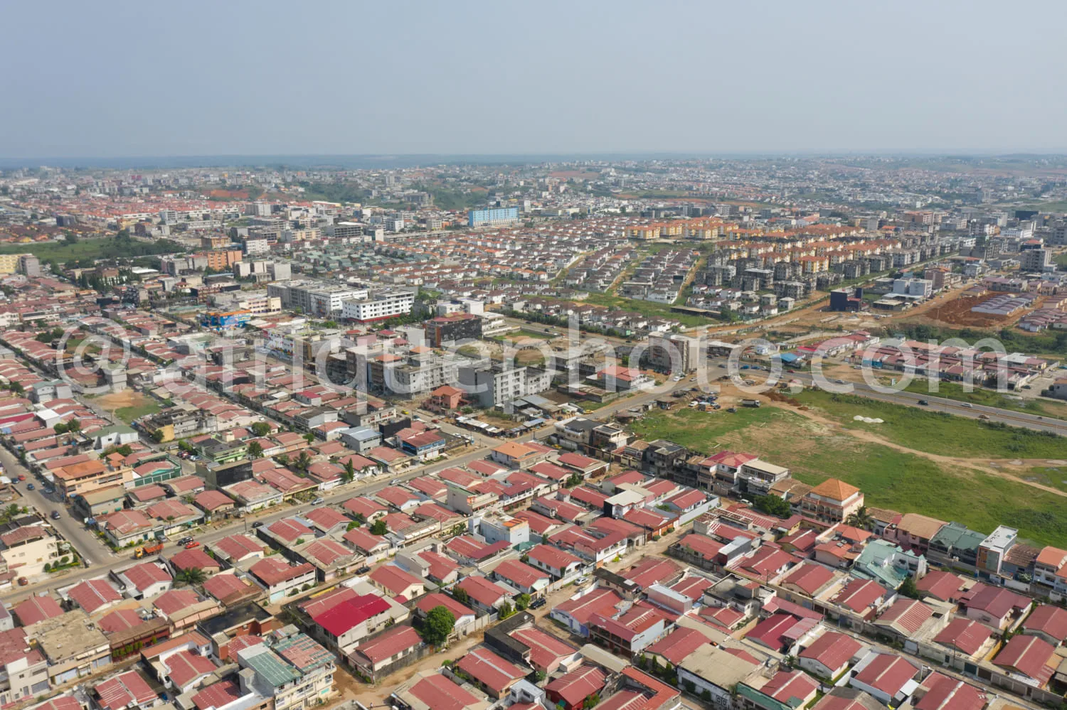 Africa photo — Image montrant une vue aérienne d’un quartier résidentiel composé de maisons aux toits rouges, organisées en rues rectilignes, avec des