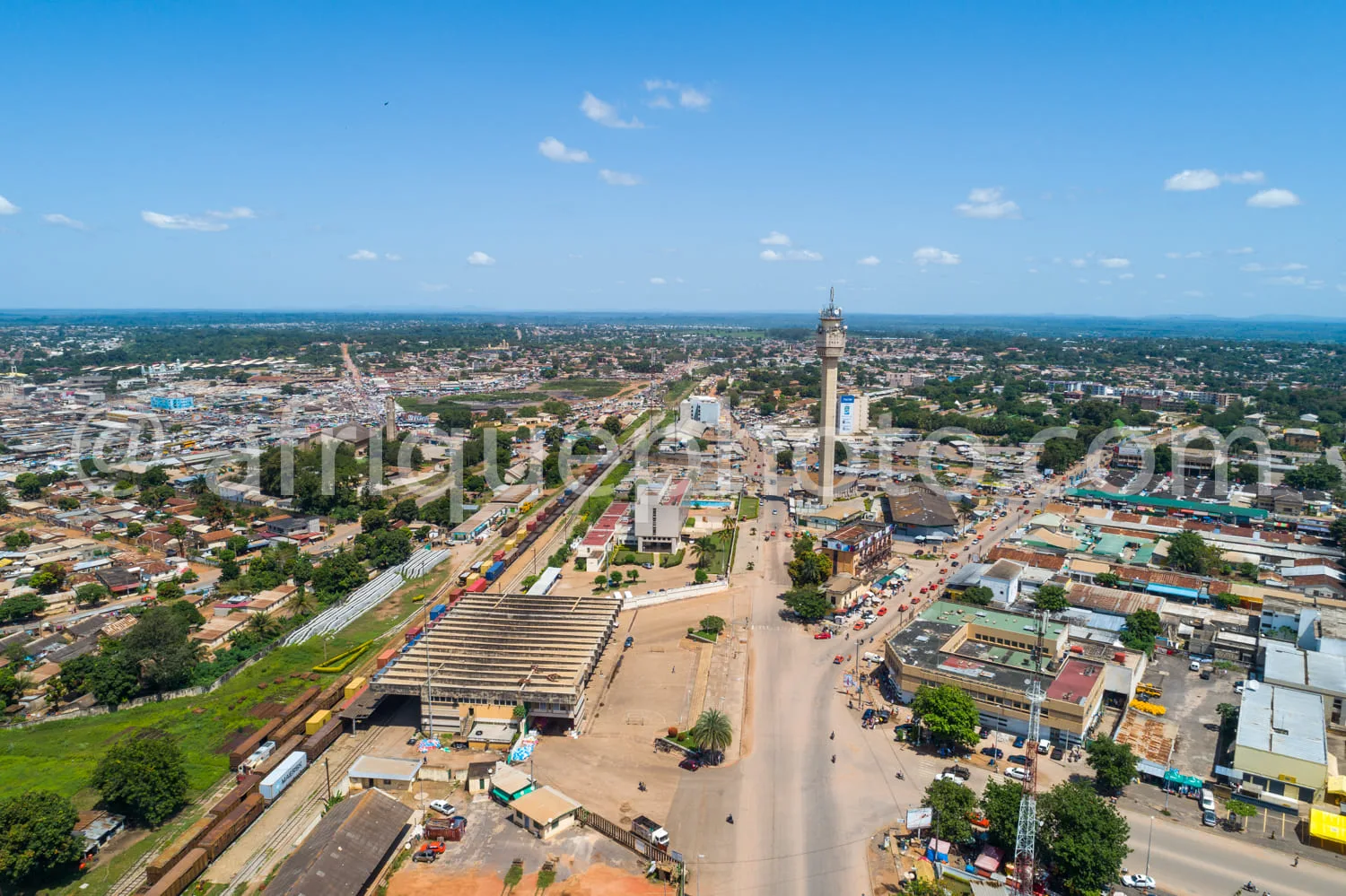 Africa photo — Image aérienne montrant une ville africaine avec une grande tour centrale, des bâtiments colorés, des marchés animés, des routes larges