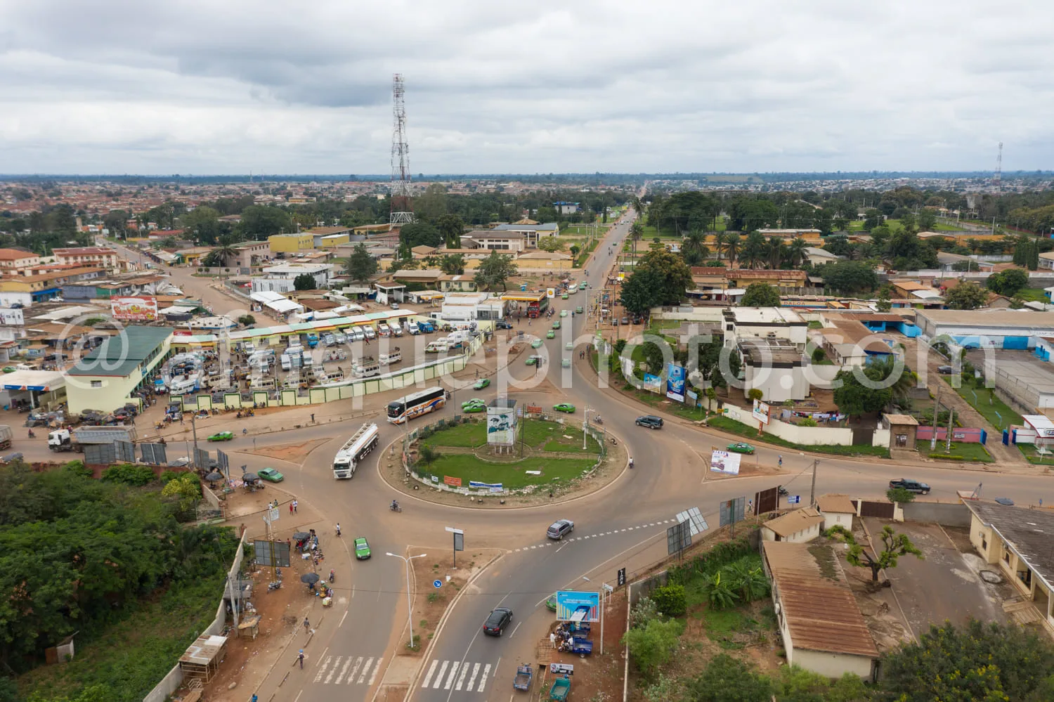 Africa photo — Image aérienne montrant une place centrale avec un rond-point végétalisé au centre, des bâtiments colorés de part et d'autre, des bus e