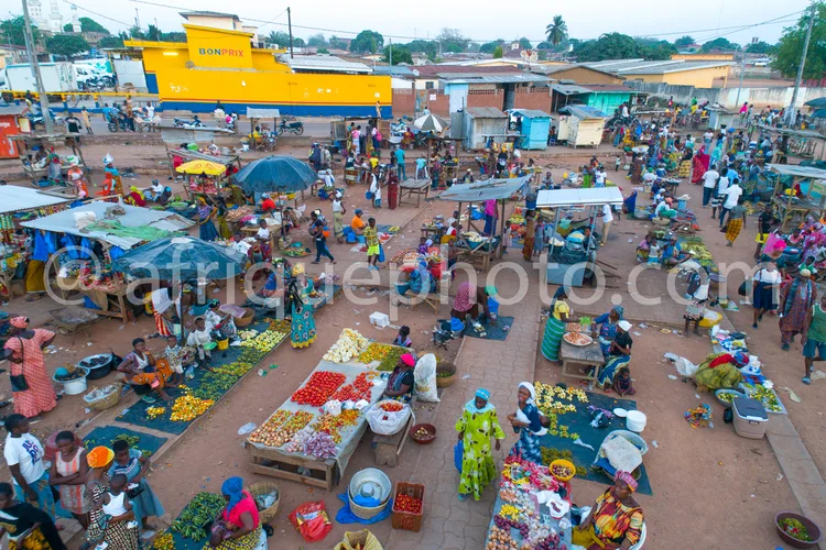 Africa photo — Vue aérienne d’un marché très animé où des marchands et clientes sont assis autour d’étals remplis de fruits, légumes et paniers coloré