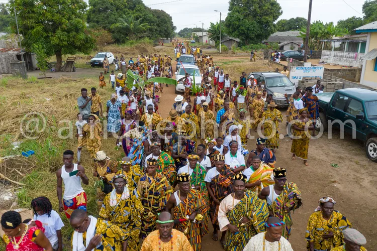Africa photo — Groupe de personnes participant à un défilé traditionnel africain, vêtues de tenues colorées aux motifs kente, avec coiffures et access
