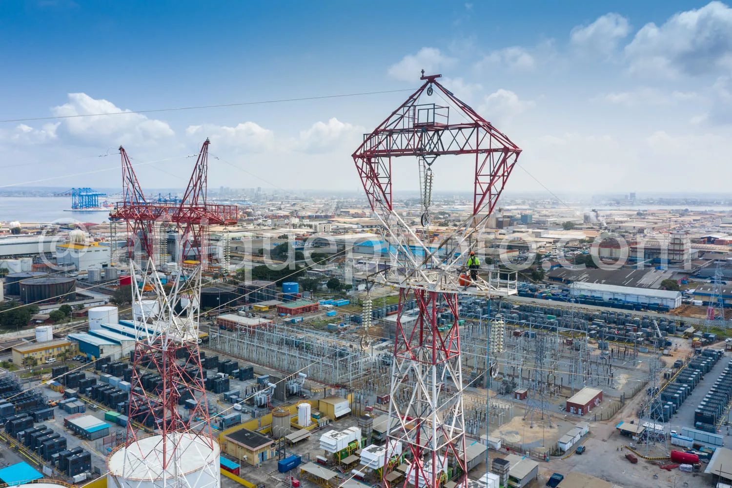 Africa photo — Image montrant une vue aérienne d’un site industriel avec deux grandes tours métalliques de transport d’électricité, des bâtiments de s