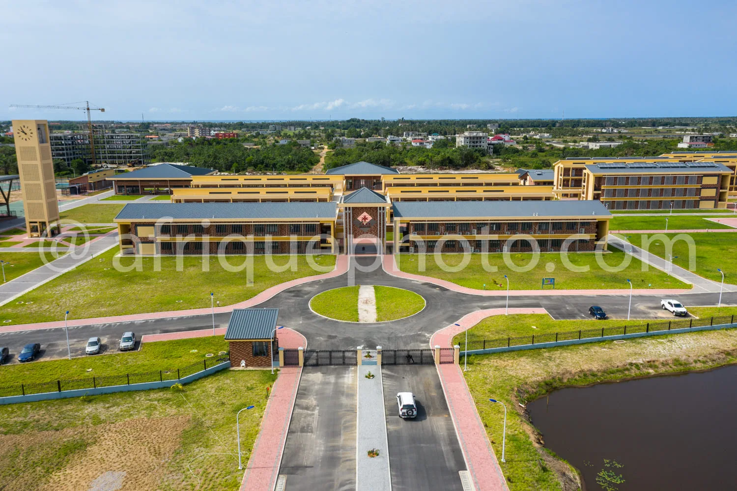 Africa photo — Vue aérienne d’un campus moderne comprenant un grand bâtiment central jaune à deux étages avec une entrée monumentale, une tour horloge