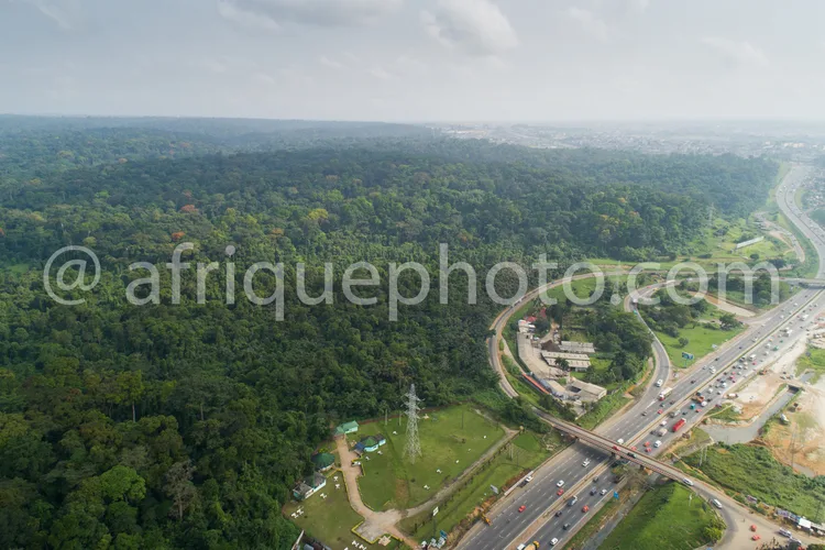 Africa photo — Image aérienne montrant un aéroport entouré d’une dense forêt tropicale luxuriante, avec une autoroute et des routes très fréquentées e
