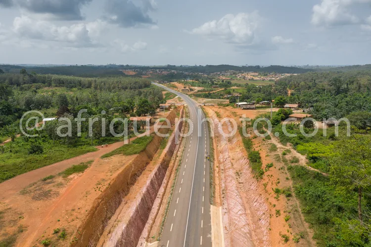 Africa photo — Vue aérienne d'une route asphaltée en cours de construction, entourée de végétation dense, de champs et de quelques habitations isolées