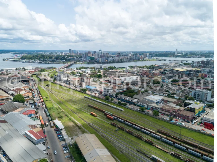 Africa photo — Une vue aérienne d'une ville portuaire où l'on distingue des gratte-ciels au centre, une voie ferrée avec des wagons en mouvement, des