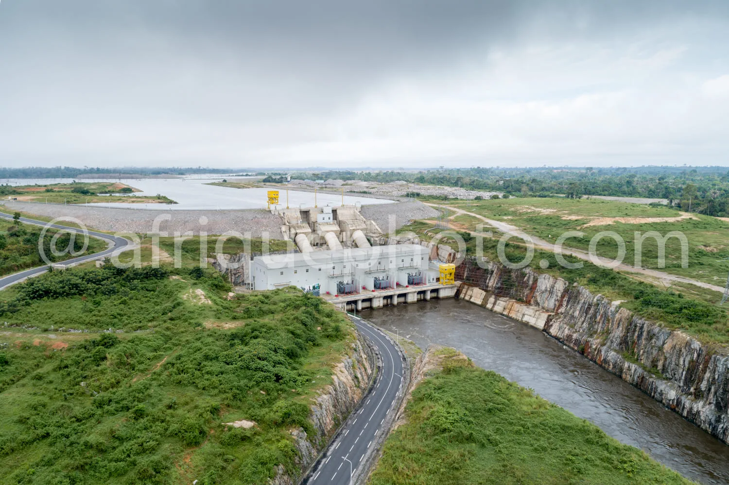 Africa photo — Vue aérienne d’un barrage hydroélectrique imposant, avec une route sinueuse le long d’une falaise rocheuse et un large réservoir d’eau