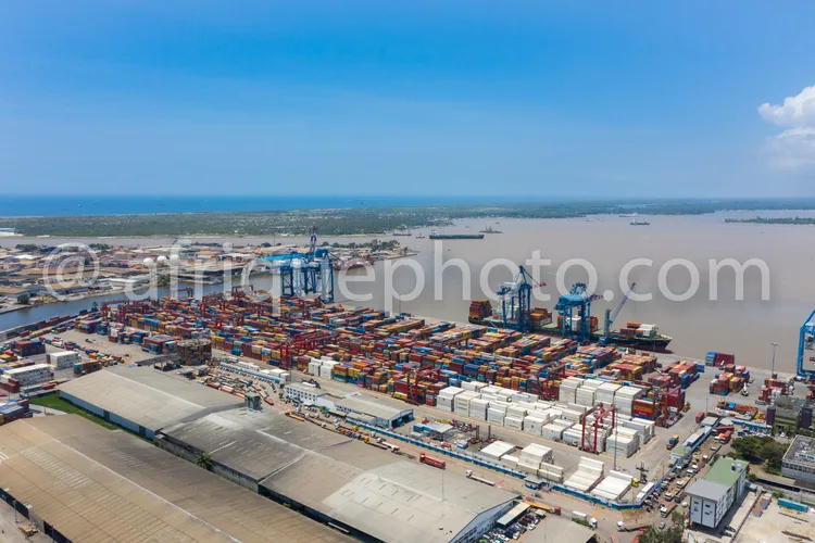 Africa photo — Vue aérienne d'un port maritime très actif avec des rangées de conteneurs colorés empilés, des grues géantes en mouvement et un fleuve