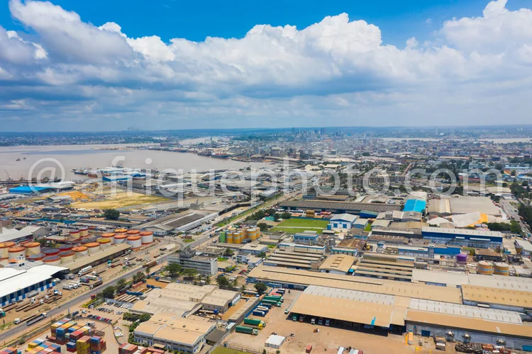 Africa photo — Image aérienne montrant un port industriel avec des entrepôts colorés, des docks et des zones de stockage organisées, sous un ciel déga