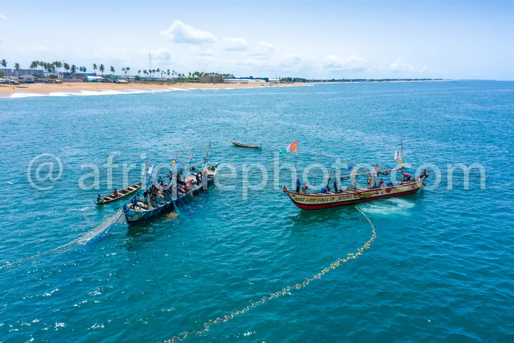 Africa photo — Vue aérienne de trois bateaux de pêcheurs traditionnels colorés, reliés par une corde, naviguant sur une mer turquoise à proximité d'un
