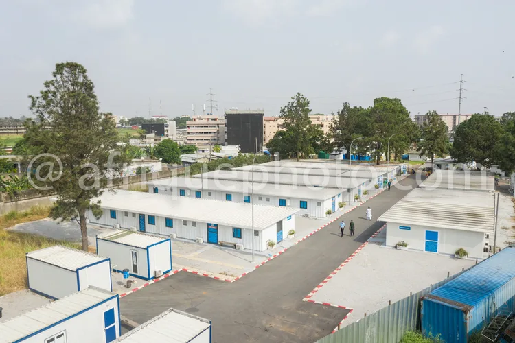 Africa photo — Vue aérienne d’un ensemble de bâtiments modulaires blancs et bleus, disposés en rangées avec des allées goudronnées et des bordures rou