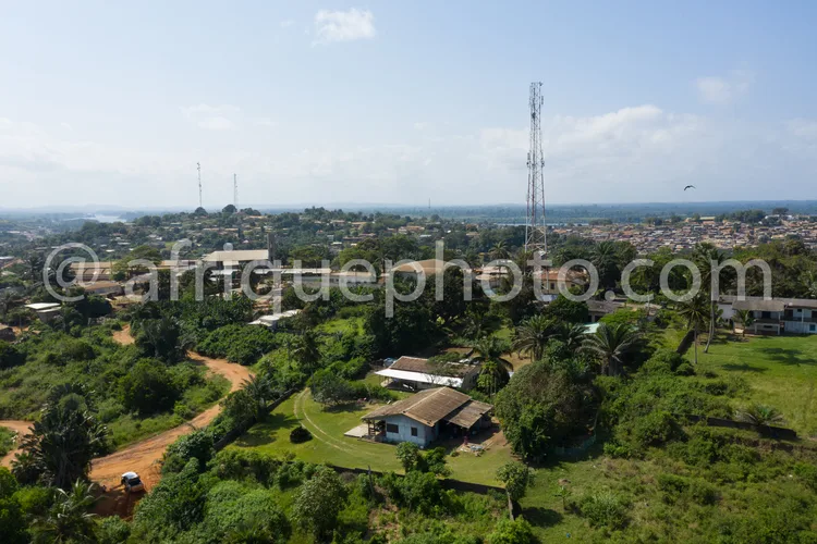 Africa photo — Image aérienne montrant un village entouré de végétation luxuriante, avec des maisons en bordure de forêt, des routes sinueuses et des