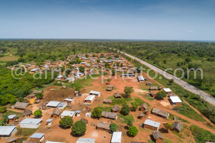 Africa photo — Vue aérienne d'un village africain traditionnel composé de maisons en torchis et de quelques toits en tôle, entouré de végétation dense
