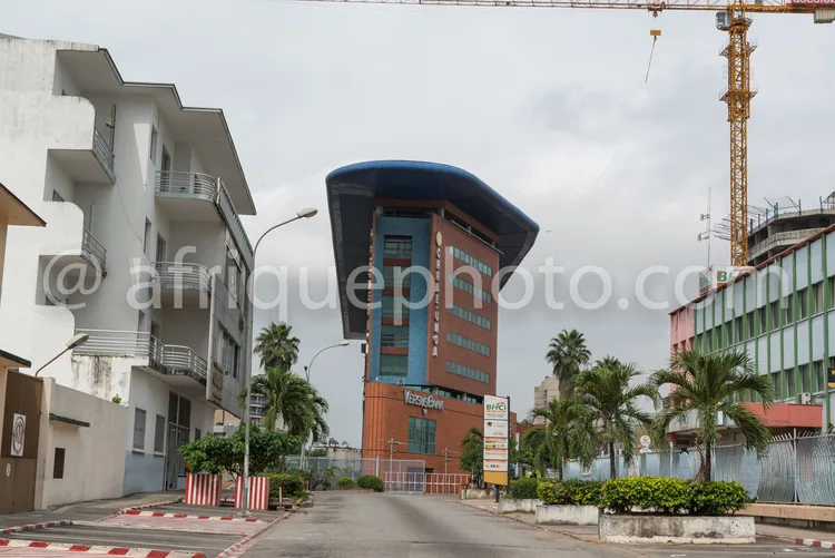 Africa photo — Vue d’un immeuble moderne aux lignes architecturales originales, avec un toit en forme de vague bleue, entouré de bâtiments en construc