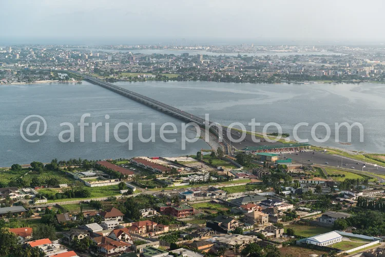 Africa photo — Un large pont métallique enjambant une étendue d'eau calme, reliant deux parties d'une ville dense entourée de quartiers résidentiels e