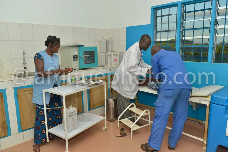 Africa photo — Trois professionnels en blouses de laboratoire travaillent ensemble dans un espace équipé de meubles bleus et blancs, utilisant du maté
