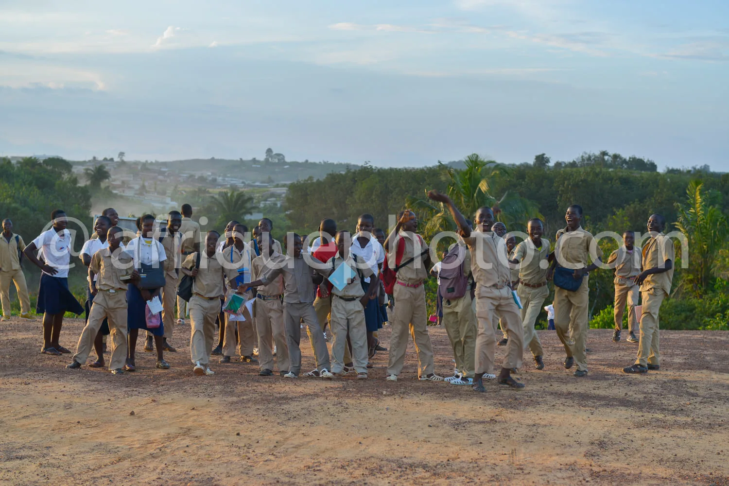 Africa photo — Un groupe de personnes vêtues d’uniformes beige, dont certains portent des casquettes et des ceintures, se tiennent debout sur un terra