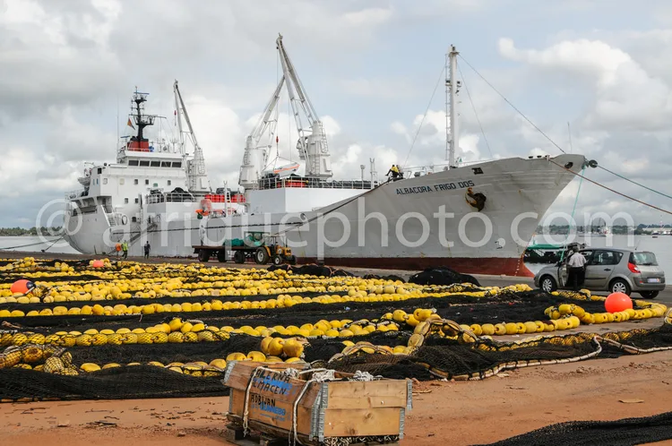 Africa photo — Un navire de pêche nommé Albacora Frigo Dos amarré au port avec des filets de pêche remplis de thons jaunes disposés sur le quai, entou