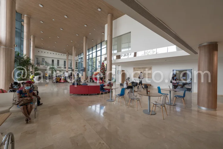 Africa photo — Une vaste salle d'attente aéroportuaire lumineuse, équipée de canapés, tables basses et chaises bleues, avec des colonnes rondes et une