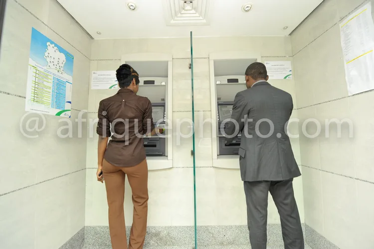 Africa photo — Deux individus dos à la caméra, un homme en costume gris et une femme en tenue professionnelle, interagissent simultanément avec deux d