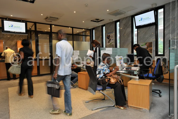 Africa photo — Une salle lumineuse avec plusieurs personnes assises à des bureaux équipés d’ordinateurs, de claviers et d’écrans. Une personne se tien
