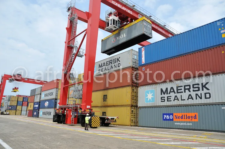 Africa photo — Un groupeur portuaire rouge soulève un conteneur Maersk-Sealand entreposé parmi d’autres conteneurs colorés (bleu, jaune, rouge) dans u