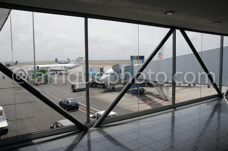 Africa photo — Intérieur d’un terminal aéroportuaire avec une grande baie vitrée offrant une vue sur trois avions stationnés sur la piste, des passere