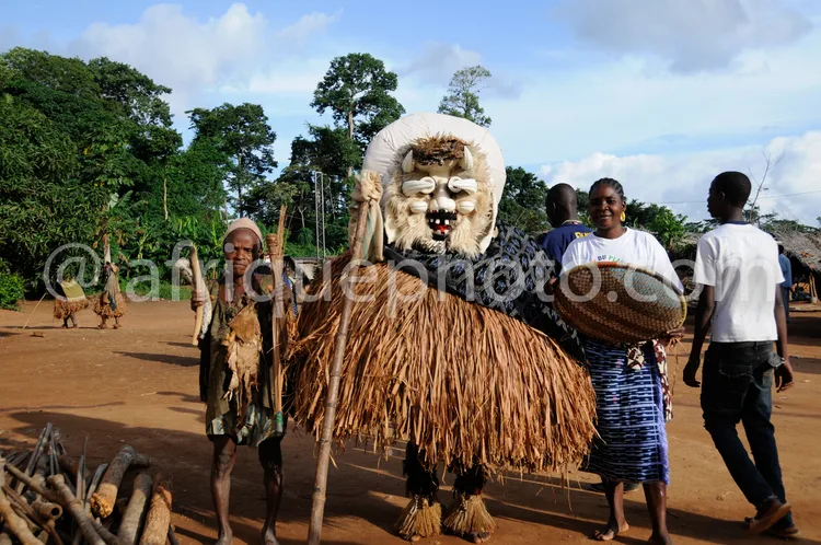 Africa photo — Un masque traditionnel africain imposant en forme de tête d'animal, fabriqué avec des fibres végétales et un tissu blanc, porté par une