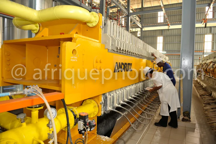 Africa photo — Une personne en blouse blanche surveille une grande machine jaune industrielle, appelée Andritz, qui produit des bobines de fil dans un