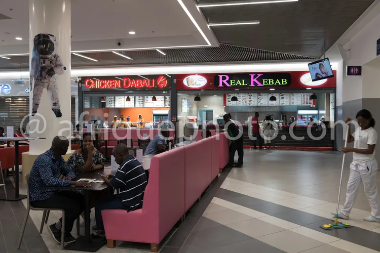 Africa photo — Intérieur lumineux d’un espace restauration aéroportuaire avec deux enseignes de fast-food, Chicken Dabali et Real Kebab, des clients a