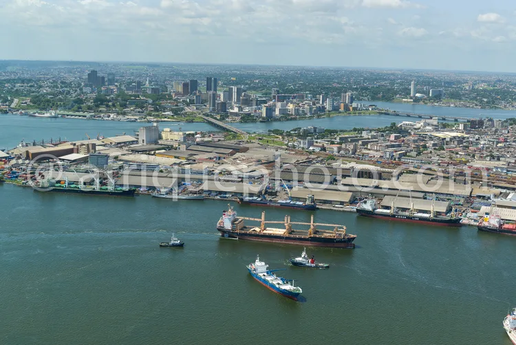 Africa photo — Vue aérienne d’un port maritime animé où l’on distingue plusieurs navires de commerce amarrés ou en navigation, des docks industriels,