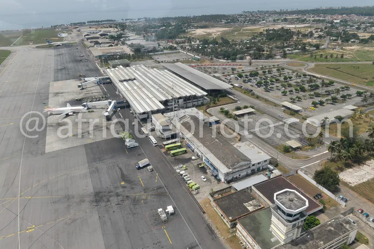 Africa photo — Vue aérienne d’un aéroport avec un avion blanc stationné devant un terminal moderne, des pistes de décollage et des zones de stationnem