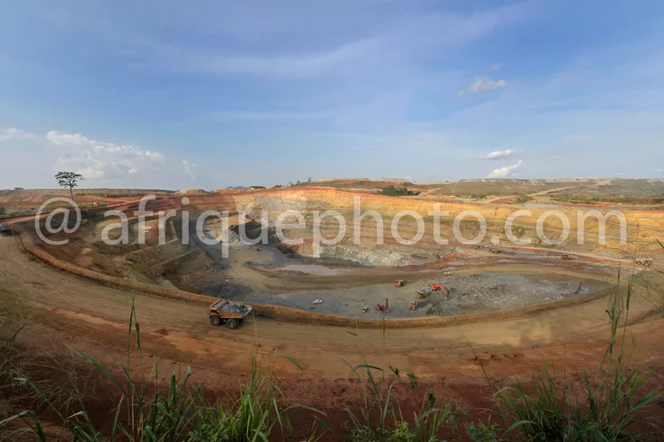 Africa photo — Vue panoramique d’une carrière minière en activité avec des engins de chantier comme un dump truck et des pelleteuses, entourée de paro