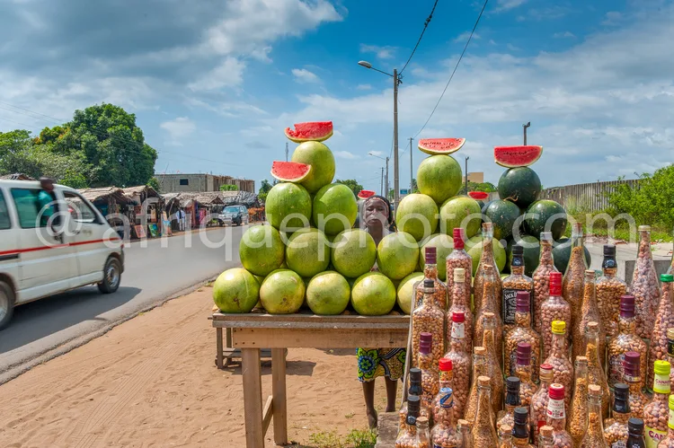 Africa photo — Un étalage de rue bien achalandé avec des melons verts et des pastèques coupées en deux posées en équilibre sur le dessus, entourés de