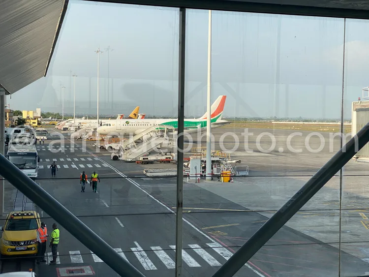Africa photo — Deux avions stationnés sur une piste d'aéroport, entourés d'agents en tenue de sécurité jaune et verte. Un véhicule jaune est visible à