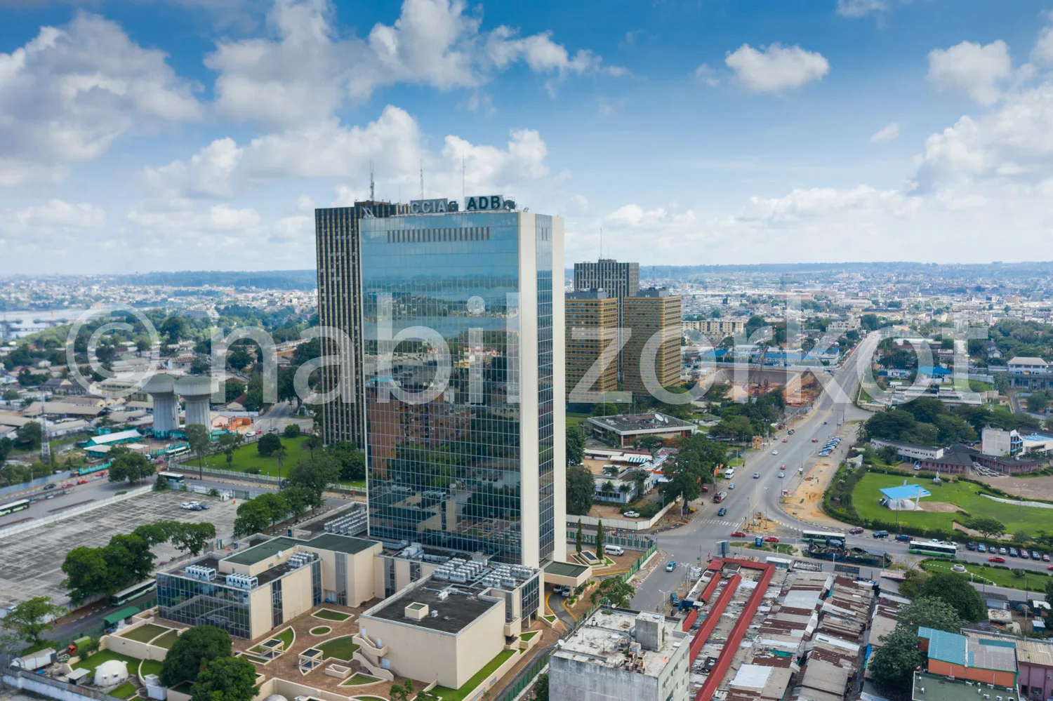 Africa photo — Vue aérienne d’un imposant gratte-ciel portant la marque ADB, entouré de bâtiments urbains, routes et espaces verts sous un ciel dégagé