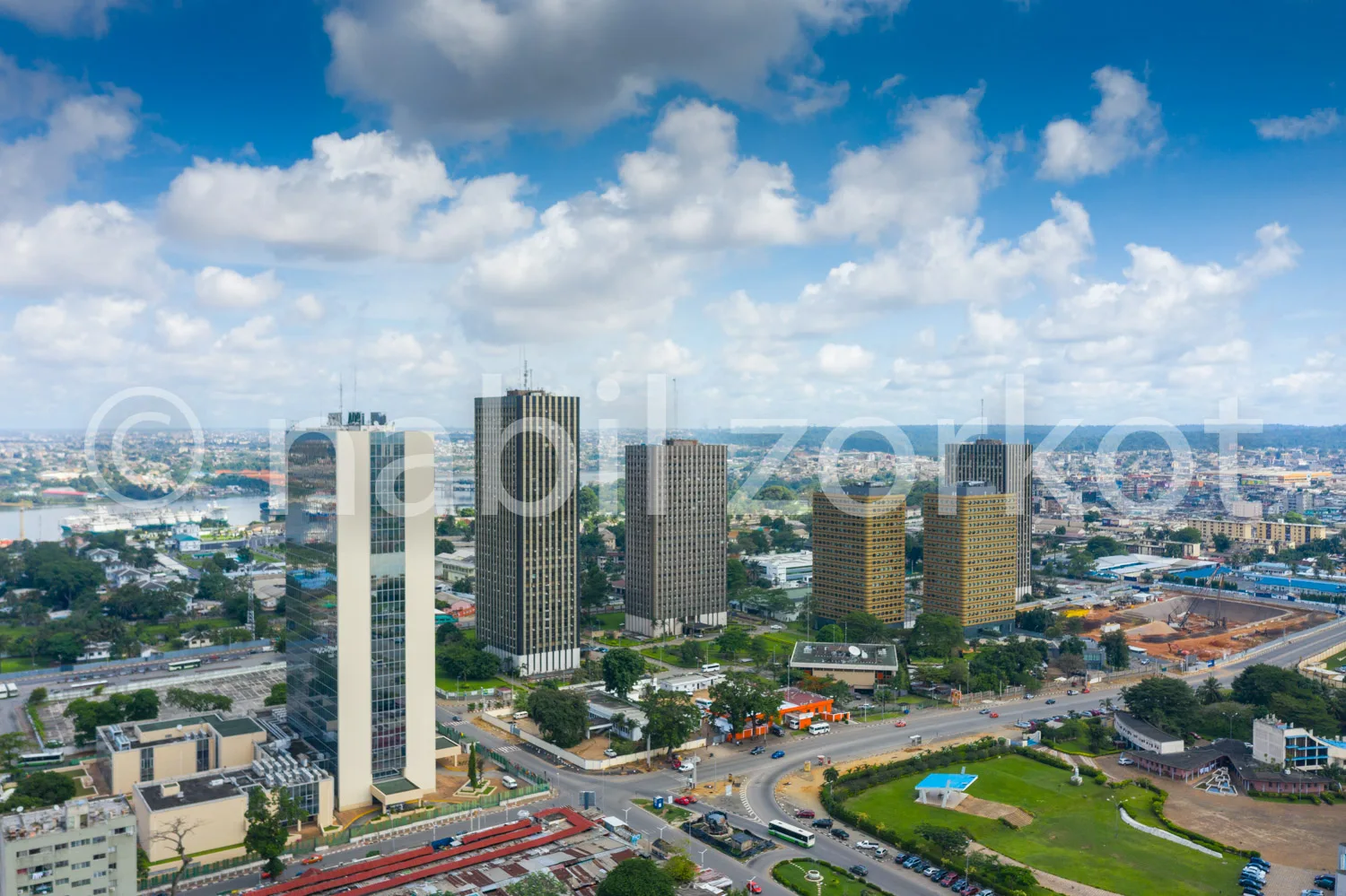 Africa photo — Vue aérienne d’un quartier urbain avec plusieurs gratte-ciels modernes, des routes bien tracées, des espaces verts et une ville en arri
