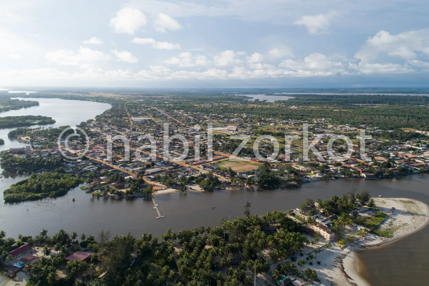 Africa photo — Vue aérienne d’un village situé le long d’une rivière aux eaux débordées, où les habitations et les routes sont partiellement submergée