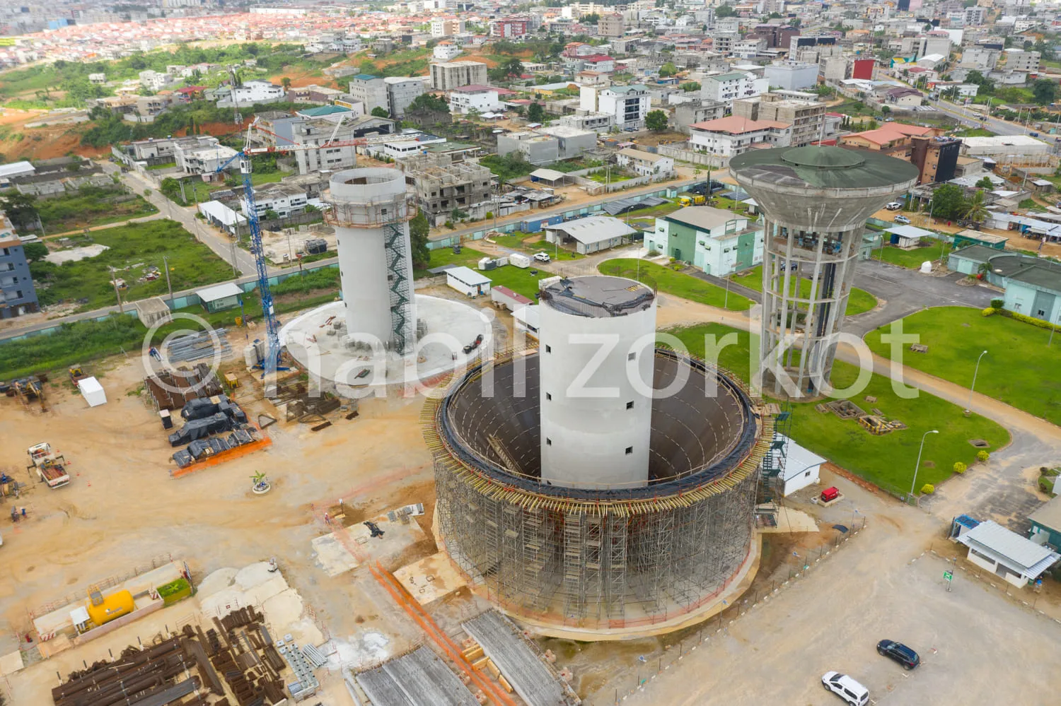 Africa photo — Vue aérienne d’un chantier de construction d’une centrale électrique en milieu urbain, montrant deux tours de refroidissement et un bât