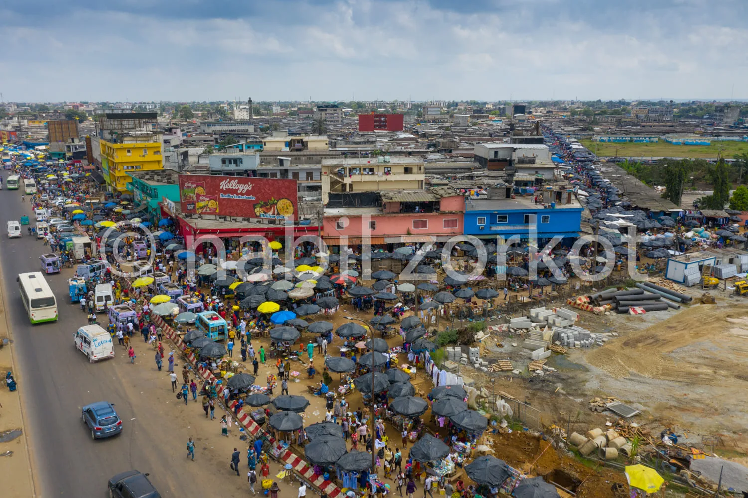 Africa photo — Vue aérienne d’un marché très animé avec des étals couverts de parasols, des vendeurs et des clients en mouvement, des véhicules et des