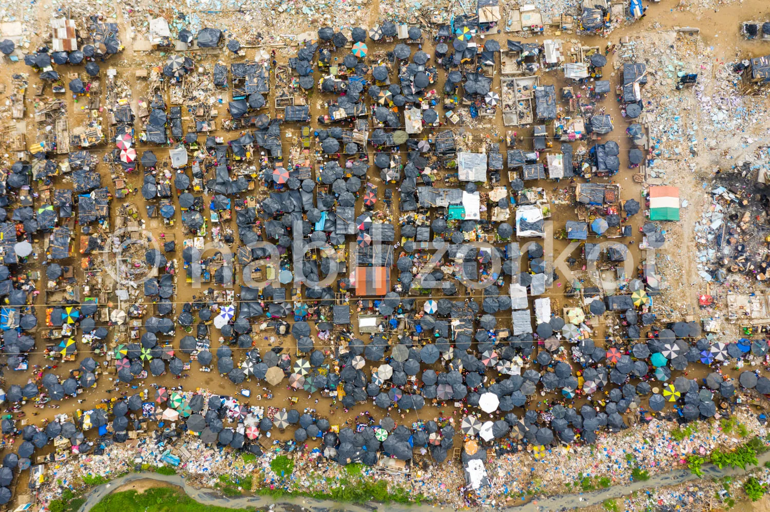 Africa photo — Vue aérienne d’un marché de plein air partiellement inondé où des centaines de personnes sont protégées par des bâches et des parapluie