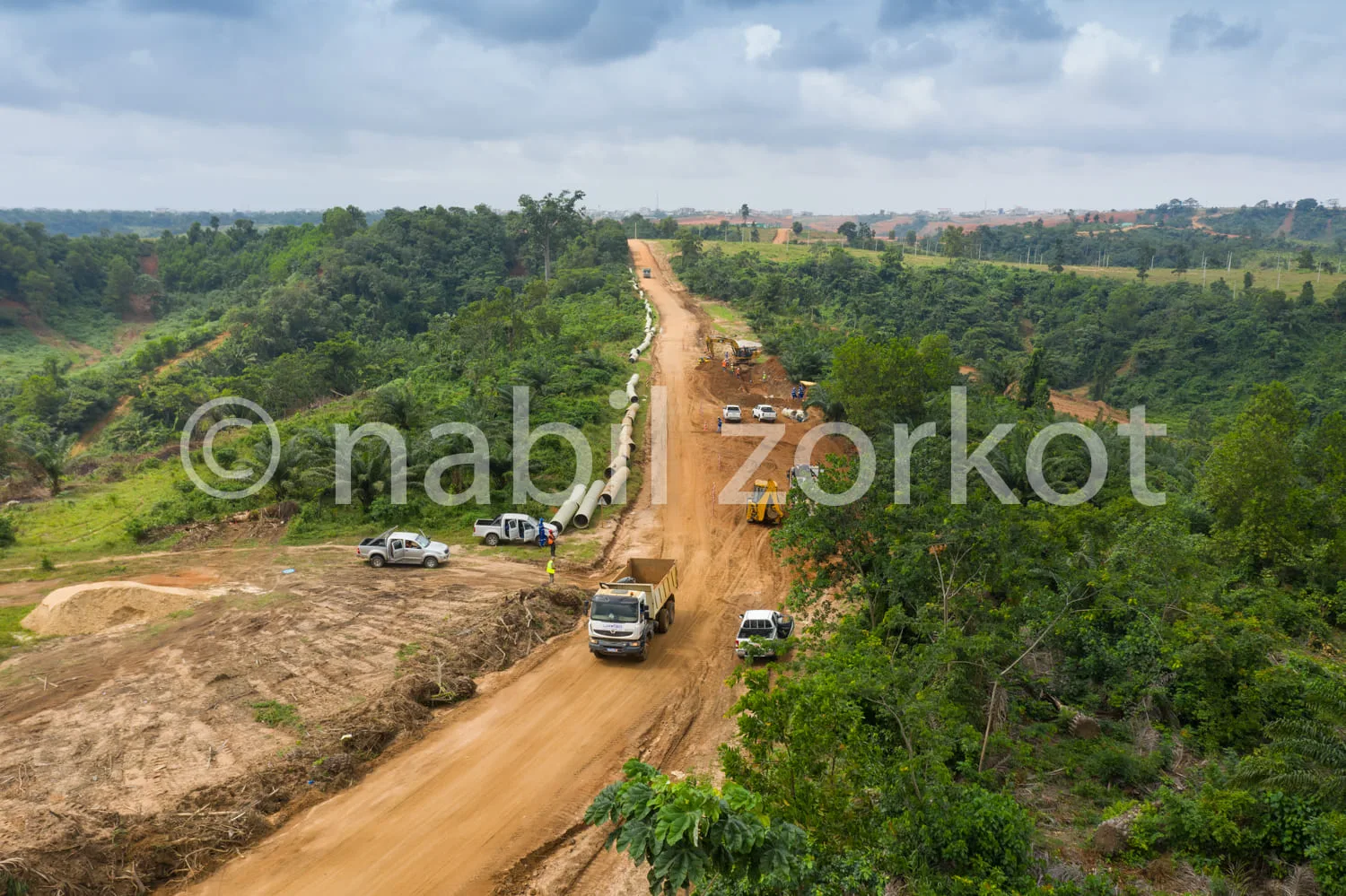 Africa photo — Vue aérienne d’un chantier routier en pleine nature : une route en terre est en cours de construction avec plusieurs véhicules et engin