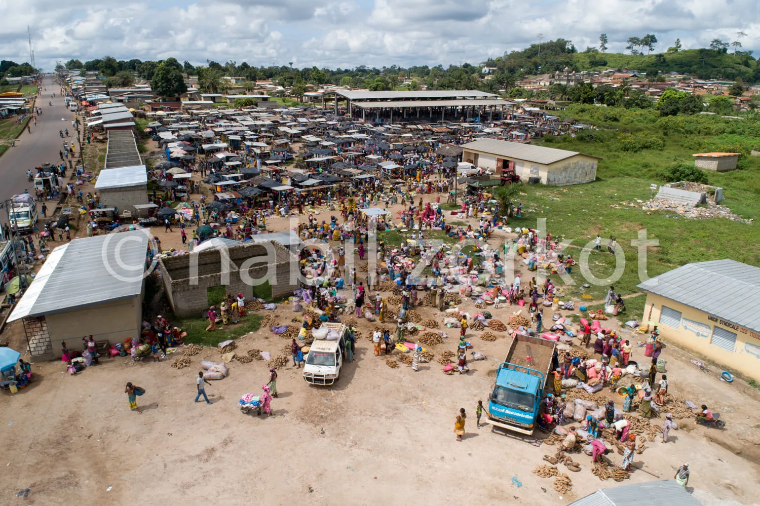 Africa photo — Vue aérienne d’un marché très animé où des centaines de personnes achètent et vendent du bois de chauffage empilé. On entend les discus