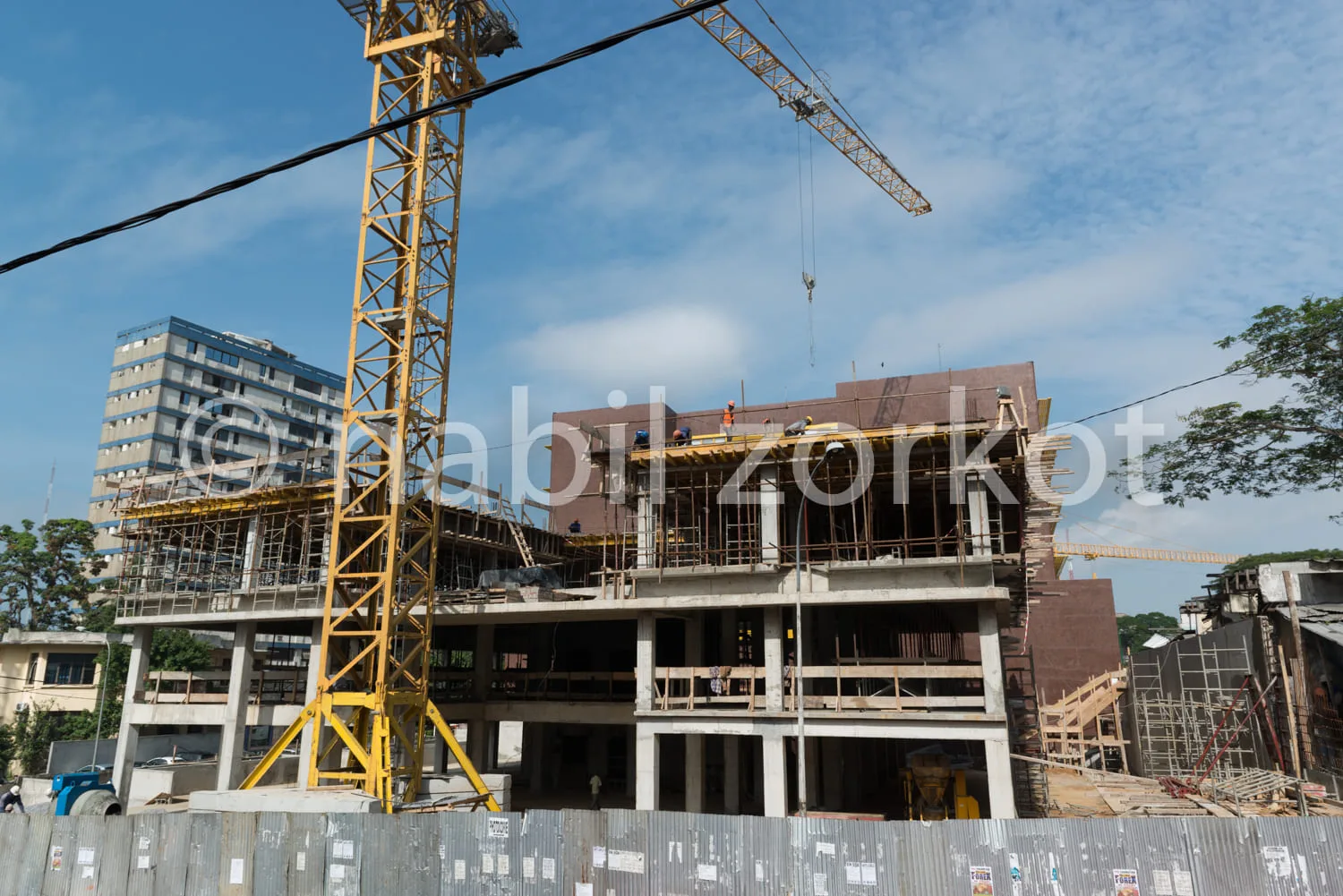 Africa photo — Image d’un chantier de construction en plein air où un immeuble de plusieurs étages est en cours d’érection. On aperçoit une grue jaune